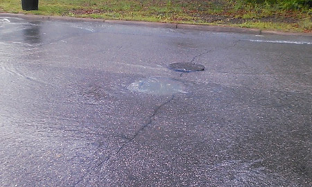 Sewage blowing the cover off a Birmingham manhole, entering a nearby storm drain, and flowing to Village Creek. Photo by Nelson Brooke
